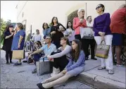  ?? LYNNE SLADKY / ASSOCIATED PRESS ?? Shoppers sit on the pavement after being evacuated from the Shops at Merrick Park after the shooting on Saturday in Coral Gables, Fla. Police say a gunman killed two and then himself.