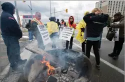  ?? The Canadian Press ?? Striking Canada Post workers walk the picket line in Mississaug­a, Ont., on Tuesday.