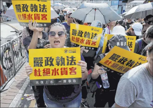 ?? Kin Cheung The Associated Press ?? Protesters hold up signs reading “Strict enforcing of law against smugglers of gray goods” at a march Saturday in Hong Kong.