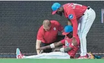  ?? WILFREDO LEE/AP ?? A trainer and Marlins left fielder Bryan De La Cruz help center fielder Jazz Chisholm Jr. after an injury Sunday in Miami.