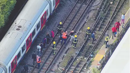  ?? AP PHOTO, ABOVE; STAFF FILE PHOTO BY ANGELA ROWLINGS, BELOW ?? EMERGENCY EXIT: Workers help people disembark a train near Parsons Green station, above, after an explosion in London yesterday. The MBTA, below, is taking preventati­ve steps to protect passengers after the London attack.