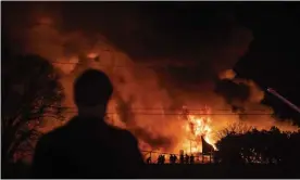  ?? Photograph: Allison Lee Isley/AP ?? A bystander watches as Winston-Salem firefighte­rs battle a fire at Weaver Fertilizer Co.