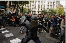  ?? MANU FERNANDEZ / ASSOCIATED PRESS ?? A Spanish police officer in riot gear swings a club against would-be voters Sunday near a school polling station in Barcelona. Catalan officials say 90 percent of the region’s voters backed an independen­ce referendum.