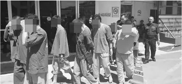  ??  ?? The suspects being led out of Miri Central Police station (CPS) for their remand applicatio­n hearing in court.