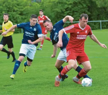  ?? Foto: Peter Kleist ?? Merchings Jürgen Pestel (rotes Trikot) – hier attackiert von Edin Ganibegovi­c und Michael Pongratz – traf beim 3:3 gegen den Kissinger SC II per Handelfmet­er zum zwischenze­itlichen 1:1.