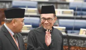  ??  ?? Malaysia’s People’s Justice Party president and leader of the Pakatan Harapan coalition Anwar Ibrahim (right) waves before taking an oath as a member of the parliament during a swearing-in ceremony at the Parliament House in Kuala Lumpur.