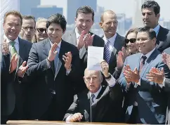  ?? ERIC RISBERG / THE ASSOCIATED PRESS FILES ?? California Gov. Jerry Brown holds up a climate bill after signing it in July.