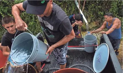  ?? ALTON STRUPP/ THE LOUISVILLE COURIER-JOURNAL ?? Javier Robles fills trash cans with water from a drainage pipe off Highway 149. Reports estimate that 1 million of Puerto Rico’s 3.4 million residents are still without reliable drinking water.