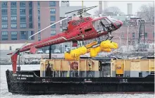  ?? MARK LENNIHAN THE ASSOCIATED PRESS ?? The helicopter in which five passengers died on Sunday night, is hoisted by crane from the East River in New York City on Monday.