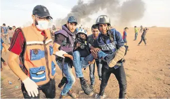  ?? PHOTO: SAID KHATIB/AFP/ GETTY ?? Flashback: Journalist­s carry a wounded colleague during clashes with Israeli forces.