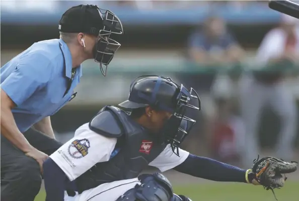  ?? Julio Cortez/the Associated Press ?? Umpire Brian debrauwere wears an earpiece that relays ball and strike calls during the Atlantic League all-star game July 10 in York., Pa. The game served as a rollout for the Trackman technology, which will be used across the league for the rest of the season.