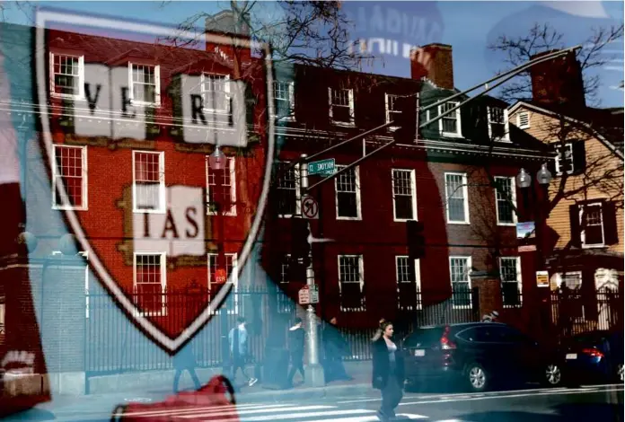  ?? JESSICA RINALDI/GLOBE STAFF/FILE ?? Pedestrian­s reflected in a window of a store selling Harvard gear in 2020. On campus today, some students say they are frustrated with university leadership.