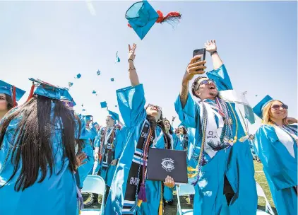  ?? PHOTOS BY GABRIELA CAMPOS/THE NEW MEXICAN ?? Students from Capital High School’s Class of 2018 throw their caps into the air after receiving diplomas at Jaguar Field on Friday morning.