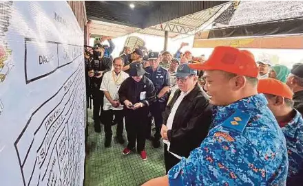  ?? PIC COURTESY OF UNIT KOMUNIKASI AWAM SARAWAK FACEBOOK ?? Datuk Douglas Uggah Embas being briefed at the temporary relied centre at Dewan Masyarakat Serian yesterday.