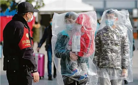  ?? FOTO REUTERS ?? Ochrana nade vše. Cestující na šanghajské­m nádraží nosí nejen roušky, ale pro jistotu si přes sebe oblékli i plastové pytle.