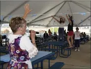  ??  ?? Oktoberfes­t attendees get in the spirit as a German Music Society vocalist leads them through a traditiona­l German dance.