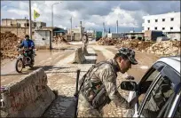  ?? PHOTOS BY IVOR PRICKETT / THE NEW YORK TIMES ?? ABOVE: A soldier works at a checkpoint on the outskirts of the northern city of Manbij, Syria, where an Islamic State group suicide bomb killed four Americans earlier this year. BELOW: Men who fled the last village held by the Islamic State wait to be questioned by coalition forces in the province of Deir el-Zour, Syria, in February.