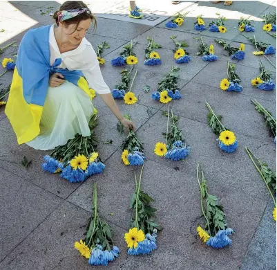  ?? (Epa) ?? Manifestaz­ione Una donna posa mazzi di fiori gialli e blu, i colori nazionali ucraini, davanti al Palazzo delle Nazioni di Ginevra