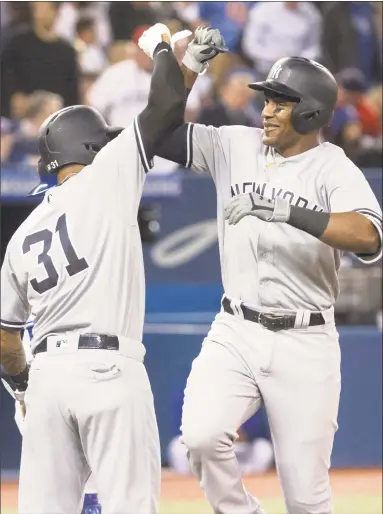  ?? Fred Thornhill / Associated Press ?? The Yankees’ Miguel Andujar, right, is greeted at home plate by Aaron Hicks after hitting a grand slam against the Blue Jays during the seventh inning of Tuesday’s win in Toronto. Hicks hit a three-run home run later in the game.