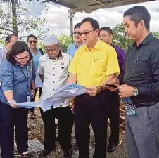  ??  ?? LO (dua dari kanan) bersama Mohamad Asman (kanan) dan Anielia (kiri) melihat pelan Projek RMR Kampung Bunga Rampai, Kuching.