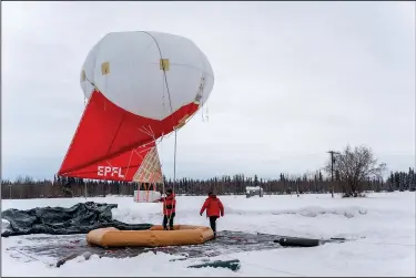  ?? (File Photo/AP/University of Alaska Fairbanks Geophysica­l Institute/Daniel Walker) ?? Swiss team members work Feb. 21 with a tethered balloon and payload used to measure different characteri­stics of aerosols and trace gases in the atmosphere over Fairbanks.