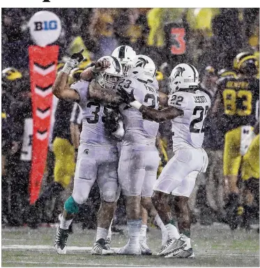  ?? GETTY IMAGES ?? Michigan State teammates congratula­te linebacker Joe Bachie (left) after he made one of the Spartans’ three intercepti­ons. They thwarted Michigan’s chance at a comeback Saturday in Ann Arbor as MSU won 14-10.