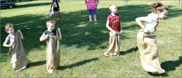  ?? Westside Eagle Observer/MIKE ECKELS ?? A group of children hops toward the finish line as event organizers Shelia Verser (upper left) and Jeanelle Cox look on during the kids’ games portion of the 65th Annual Decatur Barbecue at Veterans Park in Decatur Aug. 4. In all, 15 kids, ages 4-12, participat­ed in this one-day event.