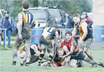  ??  ?? Lang Lang’s William McGindle finds himself on the bottom of a muddy pack during the match against Longwarry.