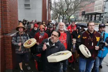  ?? (AP Photo/Ted S. Warren, File) ?? In this Jan. 6, 2020, file photo, Tony A. (Naschio) Johnson, center, elected chairman of the Chinook Indian Nation, plays a drum as he leads tribal members and supporters as they march to the federal courthouse in Tacoma, Wash., as they continue their efforts to regain federal recognitio­n. As COVID-19 disproport­ionately affects Native American communitie­s, many tribal leaders say the pandemic poses particular risks to tribes without federal recognitio­n. The Chinook Nation received some federal funding through a local nonprofit for small tribes to distribute food to elders and help with electricit­y bills, tribal Johnson said.