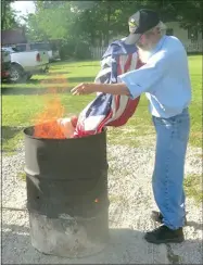  ?? Westside Eagle Observer/SUSAN HOLLAND ?? Will Crose, past first vice-commander for the John E. Tracy American Legion post, oversees the burning of a retired American flag. Members of the Gravette group hold a flag retirement ceremony each year to retire flags which become faded and worn and...