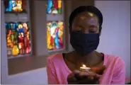  ?? DENIS FARRELL - THE ASSOCIATED PRESS ?? A worshipper wearing a face mask, holds a lit candle prior to a morning Christmas Mass at the Rosebank Catholic Church in Johannesbu­rg, Friday, Dec. 25.