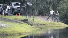  ?? Drew Martin/The Island Packet via AP ?? Law enforcemen­t officers with the South Carolina Department of Natural Resources take pictures of the site on Hilton Head Island where authoritie­s say Cassandra Cline was dragged into a lagoon Monday by an alligator and died.