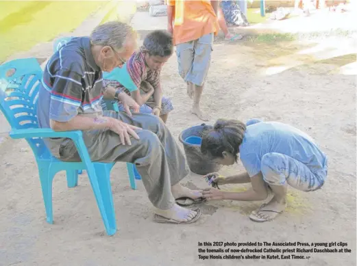  ?? AP ?? In this 2017 photo provided to The Associated Press, a young girl clips the toenails of now-defrocked Catholic priest Richard Daschbach at the Topu Honis children’s shelter in Kutet, East Timor.