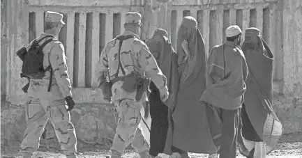  ?? JIMIN LAI, AFP ?? US Marines walk past Afghan women in burqas on Jan. 17, 2002, in Kabul.