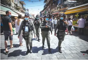  ?? (Nati Shohat/Flash90) ?? BORDER POLICE officers patrol Jerusalem’s Mahaneh Yehuda market yesterday to enforce the wearing of protective masks.