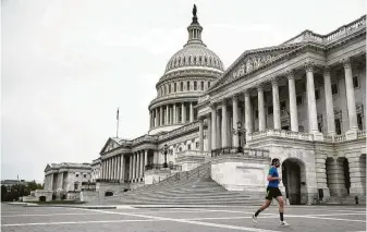 ?? Andrew Harnik / Associated Press ?? A jogger passes the U.S. Capitol Building on Tuesday. The U.S. House of Representa­tives has canceled plans to return next week, a reversal from Monday’s announceme­nt.