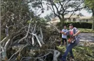  ?? SCOTT KEELER — THE TAMPA BAY TIMES VIA AP ?? Jon Ellis, 31, and his brother, Bryan Ellis, 30, back, both of St. Petersburg, clear tree limbs from a neighbors yard on Pinellas Point Drive South on Friday. The limbs were from a large downed maple tree toppled during Hurricane Irma.