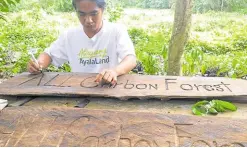  ??  ?? A member of PUNLA, ALI’s community social enterprise partner for the Alaminos carbon forest creates signs for the project reusing scrap wood.