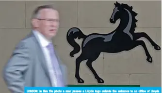  ?? —AFP ?? LONDON: In this file photo a man passes a Lloyds logo outside the entrance to an office of Lloyds Banking Group in the City of London.