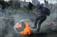  ?? ABBAS MOMANI / AGENCE FRANCE-PRESSE ?? A Palestinia­n protester kicks a flaming tire during clashes with Israeli forces in the West Bank city of Ramallah on Monday.