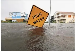  ?? — Reuters ?? Rising dangers: Flood waters lapping at a high water warning sign that was partially pushed over by Hurricane Florence on Oak Island, North Carolina.