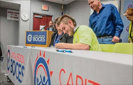 ?? Photos by Paul Buckowski / Times Union ?? Dan Corbett, right, looks on as BOCES student Harley Butler takes part Thursday in the National Signing Day ceremony in Latham.