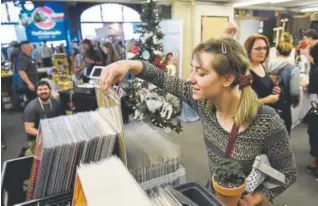  ?? Seth McConnell, Special to The Denver Post ?? Julia Johnson checks out art prints at the Arsenal Ware booth during the Denver Holiday Flea at Sports Castle on Nov. 2.