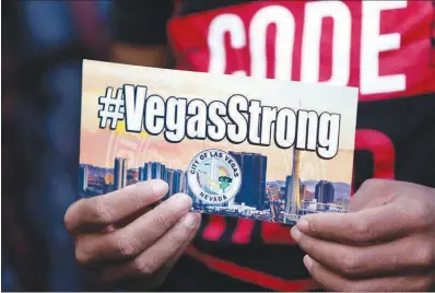 ?? STEVE MARCUS ?? A man holds a sign with a Vegas Strong hashtag on Monday at Las Vegas City Hall during a prayer vigil for those affected by the mass shooting on the Strip. In the wake of Sunday’s tragic event, more than $1r million has been pledged for victims of the...