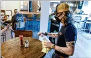  ??  ?? Bartender Jack Seale disinfects a table at Beer Wall on Penn in West Reading Thursday afternoon.