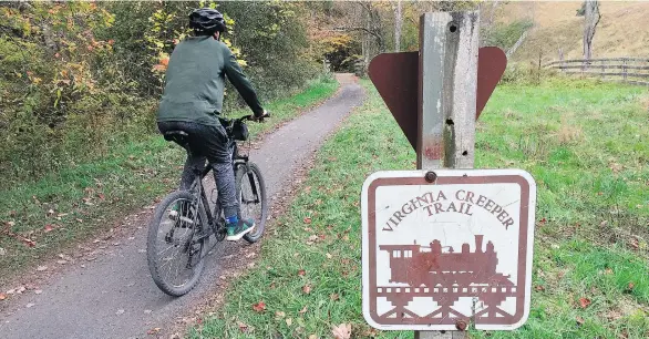  ?? PHOTOS: KAREN TESTA/THE ASSOCIATED PRESS ?? A cyclist rides through the Virginia Creeper Trail. Local outfitters rent bikes, including some with “comfort seats” for a slight upcharge.