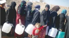  ?? — Reuters ?? Displaced people, who fled the IS stronghold of Mosul, carry empty containers as they wait in line to fill them with fuel to be used for cooking and lighting at Khazer camp on Sunday.