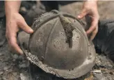  ?? Sara Gobets / Special to The Chronicle ?? Firefighte­r Geoffrey Keller examines the remains of his old fire helmet after wildfire obliterate­d his Davenport home.