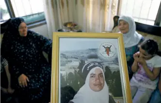  ??  ?? La famille de la Palestinie­nne Hanadi Jaradat, à Jénine en juillet 2011, conserve des portraits de la jeune femme morte dans un attentat en octobre 2003.