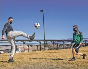  ?? GABRIELA CAMPOS/THE NEW MEXICAN ?? Recreation supervisor James Garduno and Elijah Gutierrez, 14, pass a soccer ball Thursday at Genoveva Chavez Community Center Park. A Recreation on Wheels van offering sports equipment and activities stopped at the park.